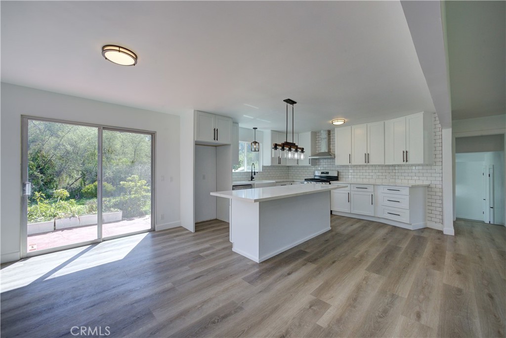 1550 Main Street Cambria, CA 93428 - Photo 6 of 9 a large kitchen with stainless steel appliances granite countertop a stove a sink dishwasher and white cabinets with wooden floor