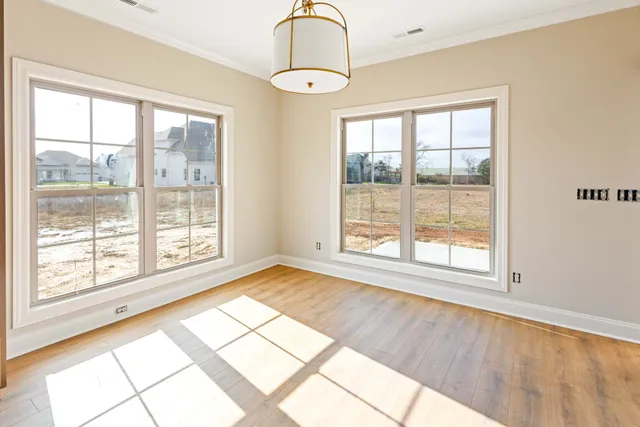 an empty room with wooden floor fireplace and windows