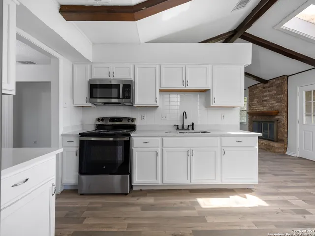 a kitchen with stainless steel appliances white cabinets a stove a sink and a microwave