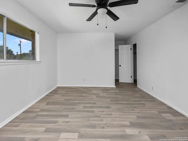 a view of an empty room with a window and wooden floor