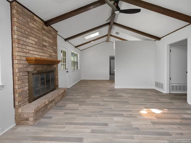 a view of an empty room with wooden floor and a fireplace