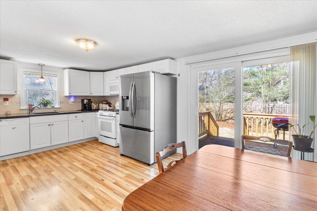 66 Barker Road Wareham, MA 02538 - Photo 10 of 18 a kitchen with a refrigerator a stove cabinets dining table and chairs