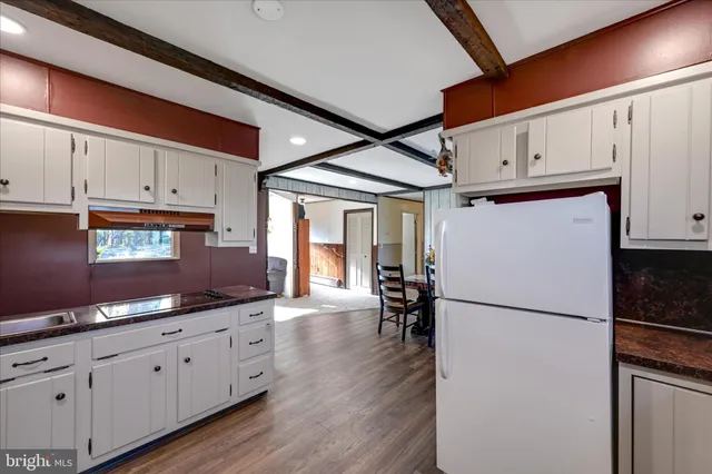 a kitchen with granite countertop a refrigerator a sink and white cabinets