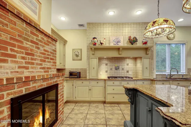 a kitchen with stainless steel appliances kitchen island granite countertop a table chairs and a refrigerator