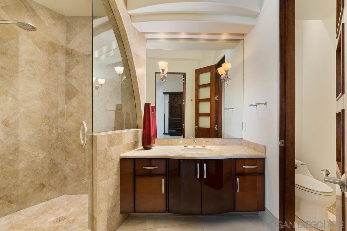 7455 Hillside Drive La Jolla, CA 92037 - Photo 20 of 33 a bathroom with a granite countertop sink a toilet and a mirror