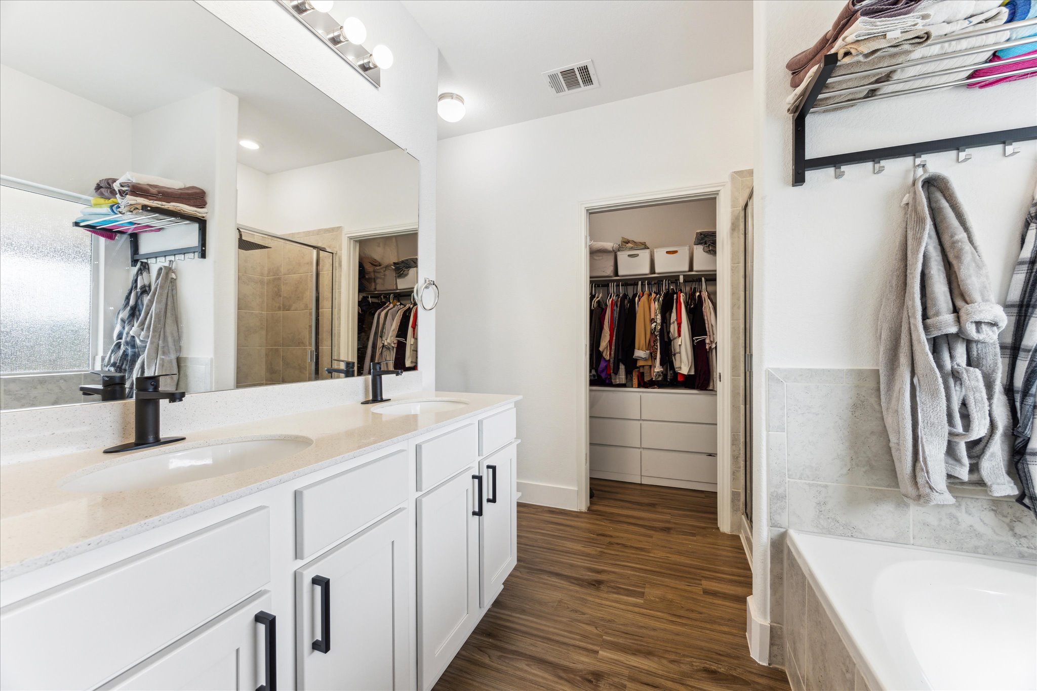 700 Legends Lane Georgetown, TX 78628 - Photo 17 of 31 Full bath with a spacious closet, double vanity, a stall shower, a bath, and wood finished floors