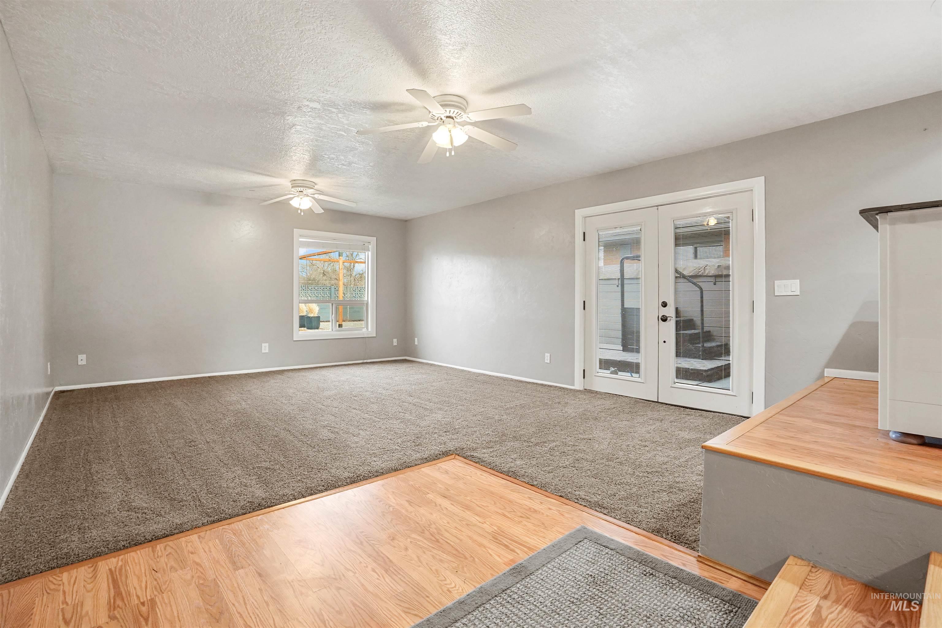 206 Pleasant Way Rupert, ID 83350 - Photo 11 of 33 Unfurnished living room featuring french doors, light wood finished floors, a textured ceiling, light colored carpet, and ceiling fan