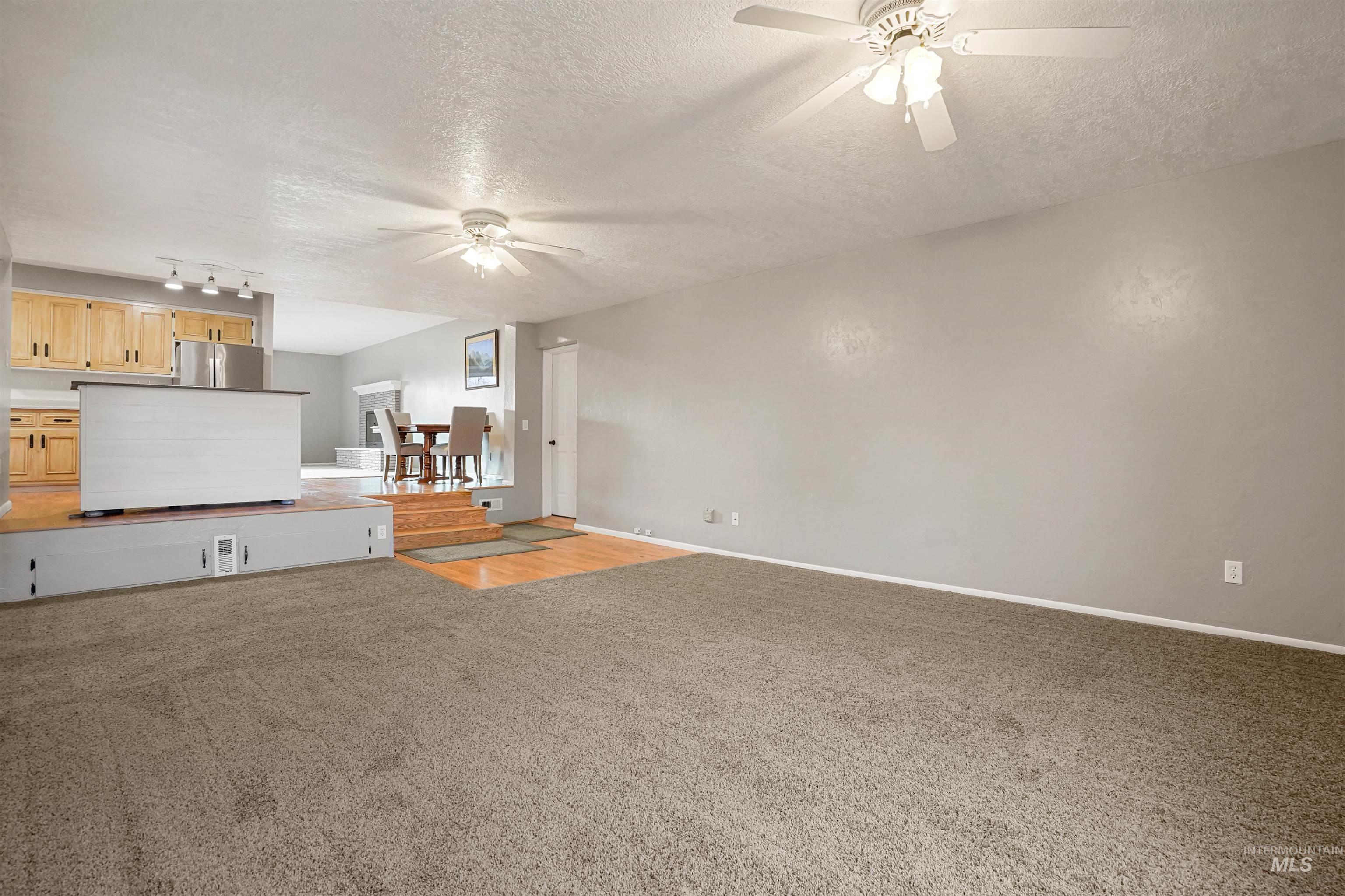 206 Pleasant Way Rupert, ID 83350 - Photo 12 of 33 Unfurnished living room with a ceiling fan, a textured ceiling, and light carpet