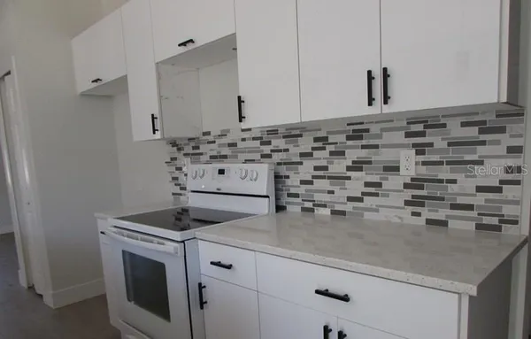 a kitchen with granite countertop white cabinets and sink