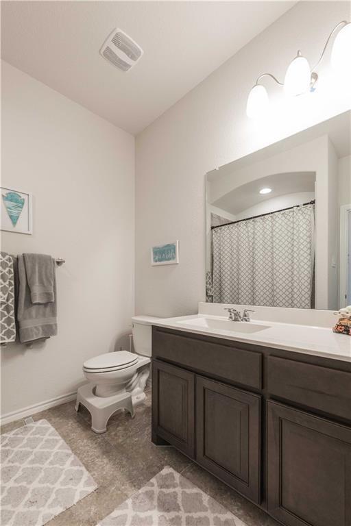 1716 Rio Penasco Road Fort Worth, TX 76052 - Photo 26 of 31 Spa-inspired bathroom featuring a dark wood vanity with dual sink configuration, white quartz countertop, large framed mirror with integrated lighting, and a patterned tile floor