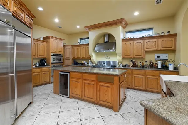 a large kitchen with stainless steel appliances kitchen island granite countertop a stove a sink and a refrigerator