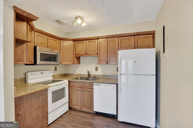 a kitchen with a sink a refrigerator a microwave and cabinets