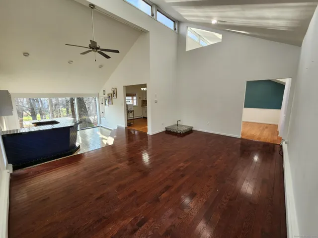 a view of kitchen and empty room with wooden floor