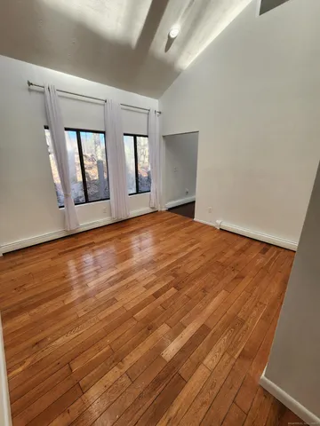 a view of an empty room with window and wooden floor