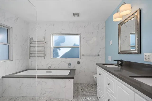 a bathroom with a granite countertop sink a mirror and a bathtub