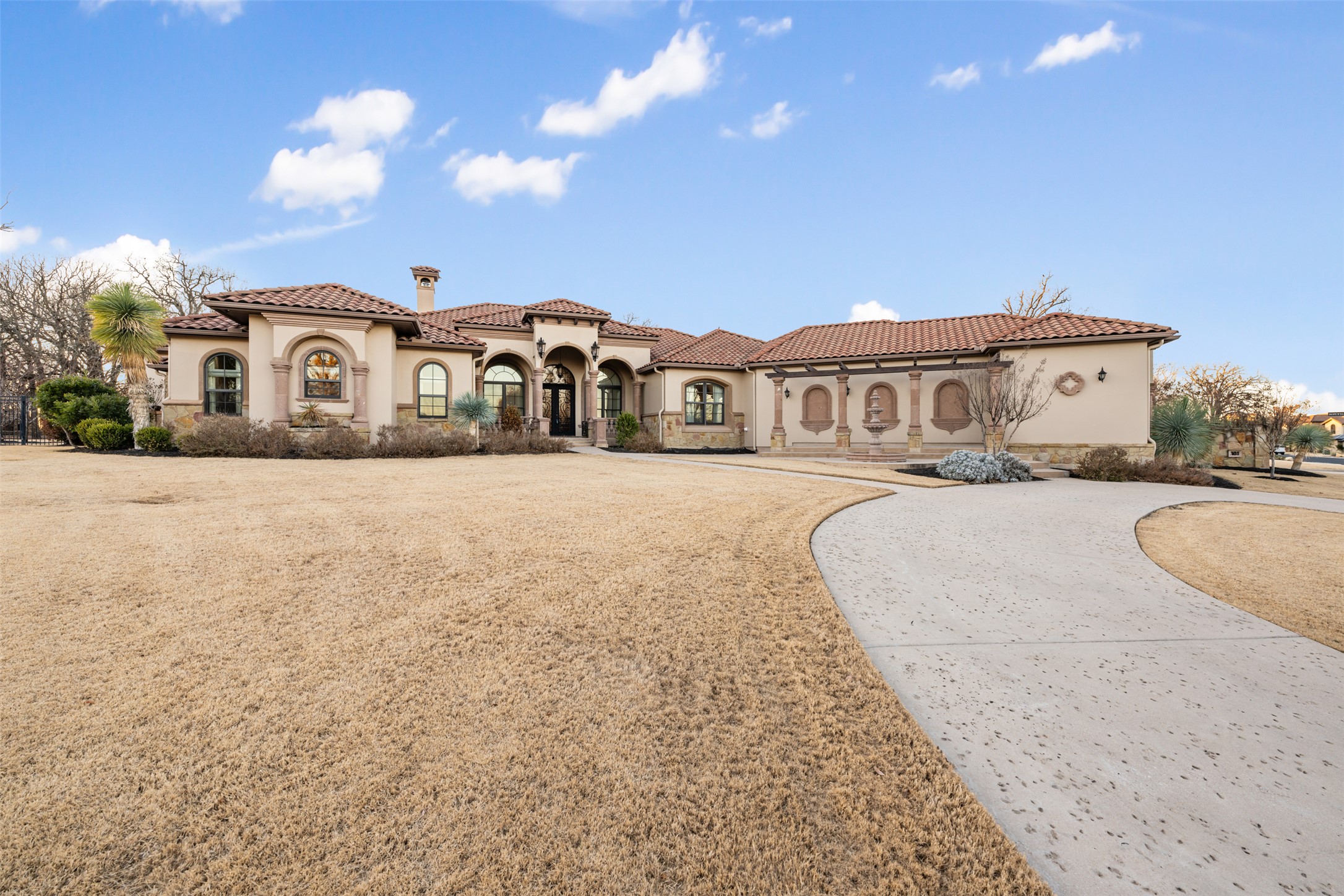 Mediterranean / spanish home featuring stucco siding, curved driveway, and a tile roof