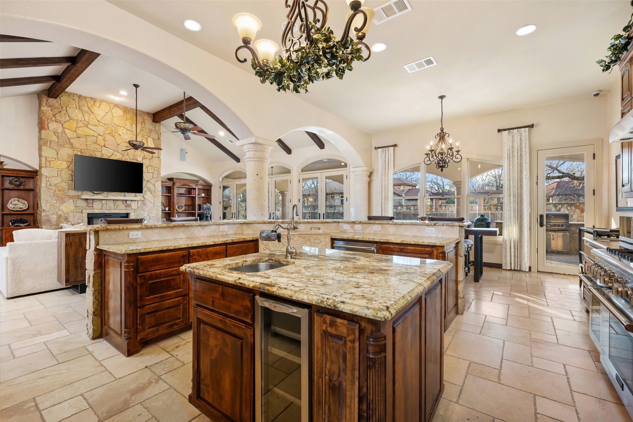 101 Hopewell Circle Georgetown, TX 78628 - Photo 38 of 38 Kitchen featuring open floor plan, light stone counters, a ceiling fan, stone tile flooring, and a stone fireplace