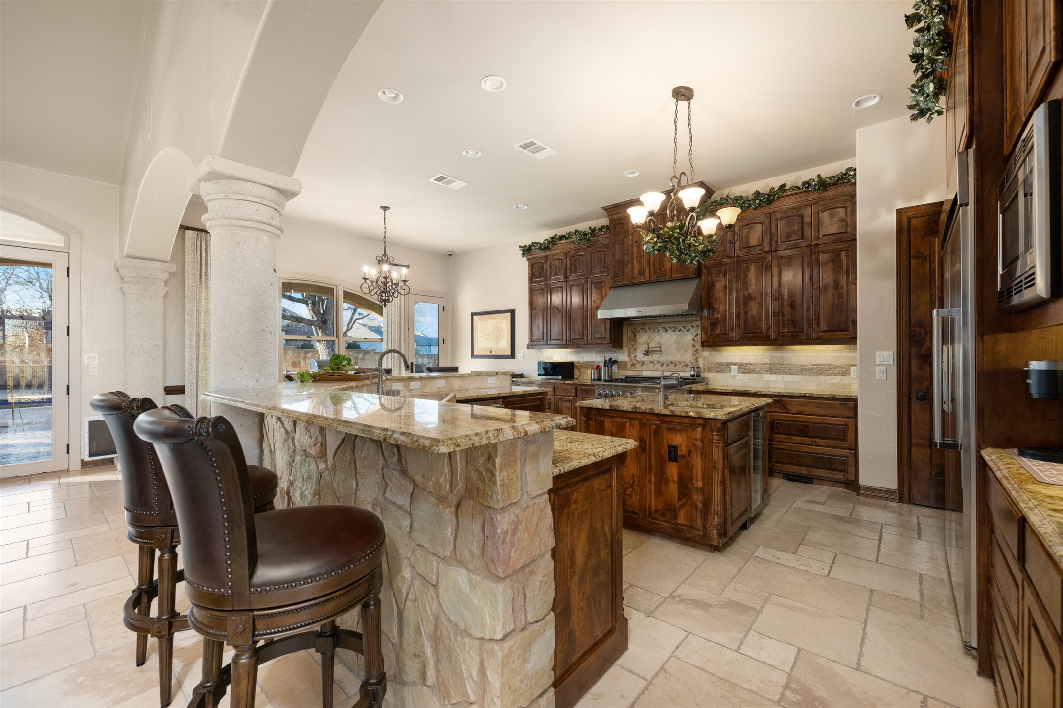 101 Hopewell Circle Georgetown, TX 78628 - Photo 9 of 38 Kitchen with hanging lights, light stone counters, decorative columns, stone tile floors, and stainless steel appliances