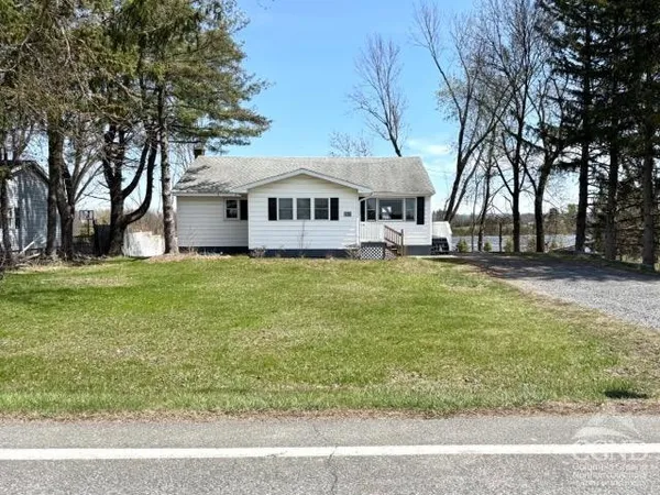 a front view of a house with a garden and trees