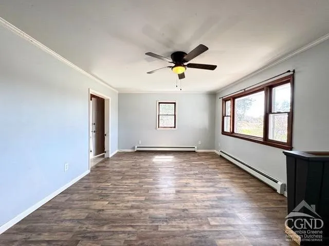 a view of an empty room with a window and wooden floor