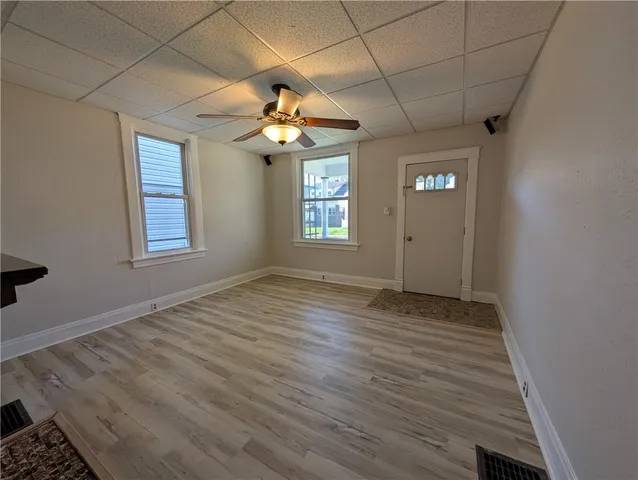 an empty room with windows and a chandelier fan
