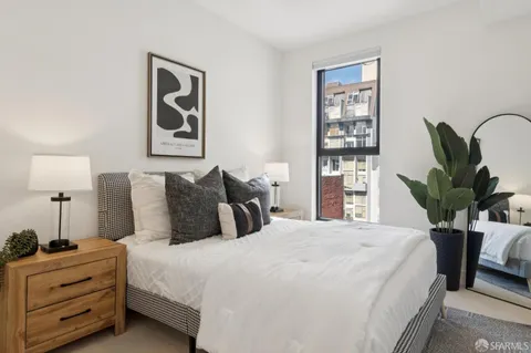 a bedroom with bed a lamp and a potted plant