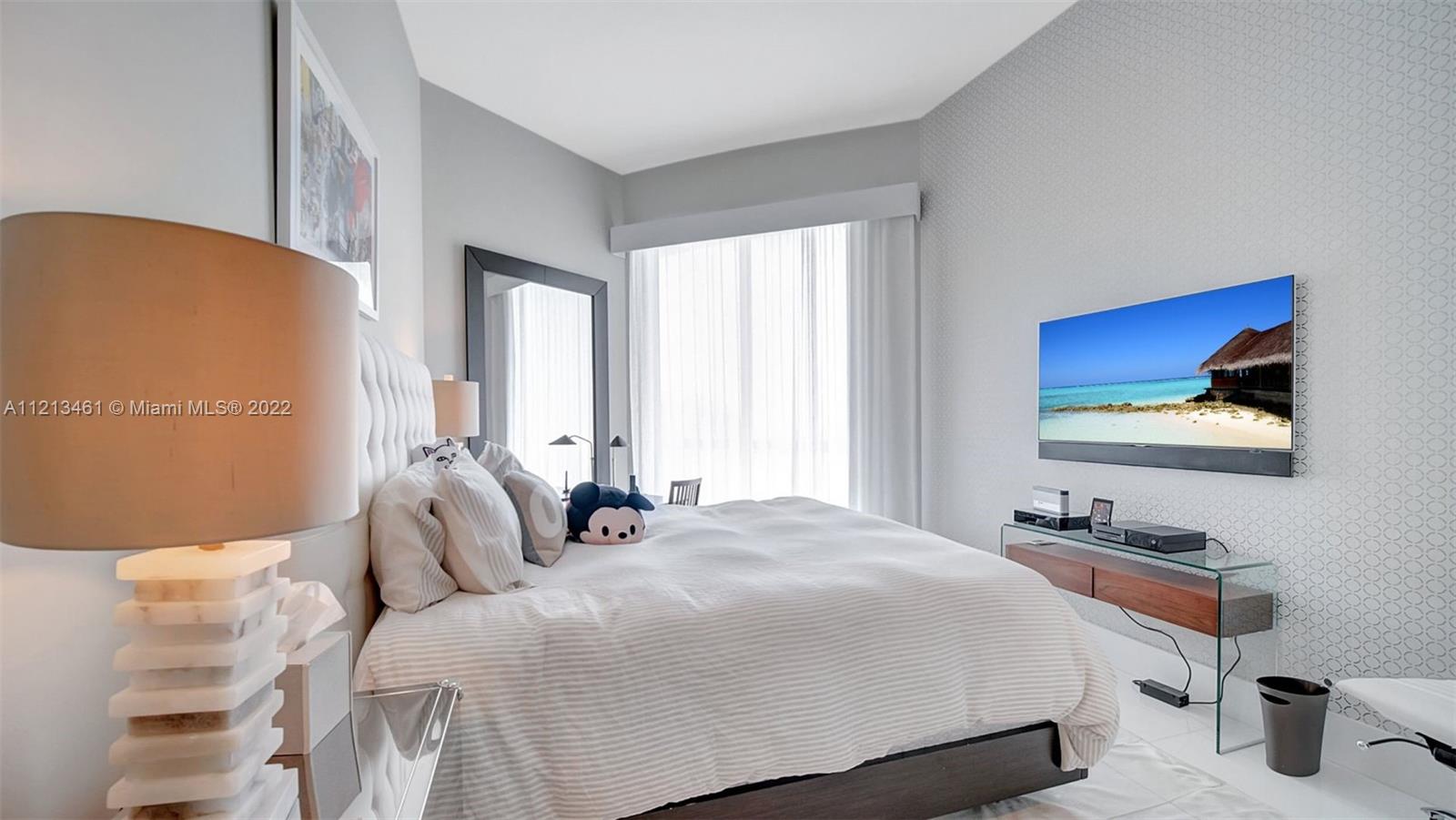 900 Brickell Key Boulevard, Unit 3103 Miami, FL 33131 - Photo 32 of 46 a bedroom with a bed and dresser with mirror