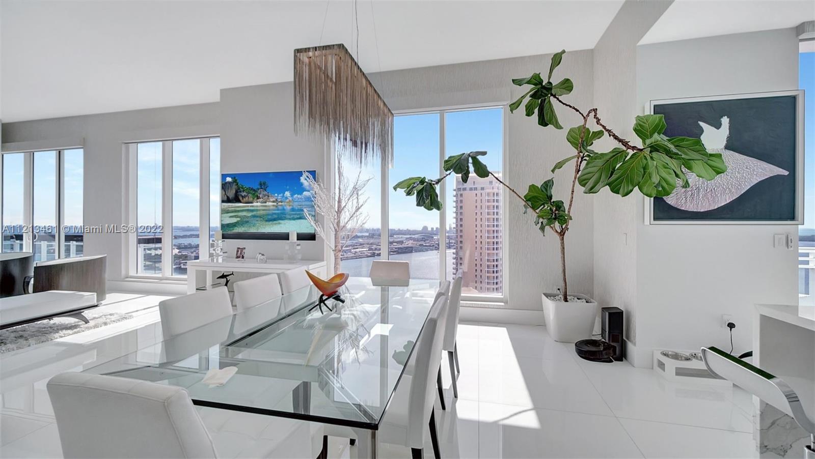 900 Brickell Key Boulevard, Unit 3103 Miami, FL 33131 - Photo 7 of 46 a dining room with furniture potted plants and wooden floor