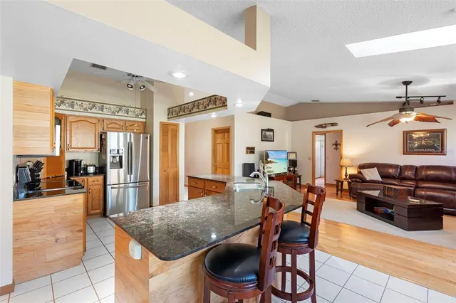 a kitchen with stainless steel appliances granite countertop a table chairs and a refrigerator
