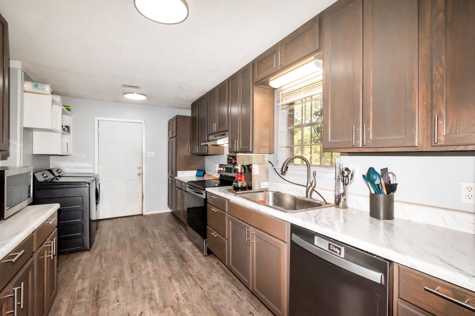 6405 1st Street Wilmer, AL 36587 - Photo 8 of 38 Kitchen with appliances with stainless steel finishes, light wood finished floors, dark brown cabinetry, and separate washer and dryer