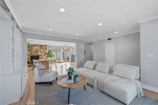 a living room with furniture a chandelier and a dining table with wooden floor