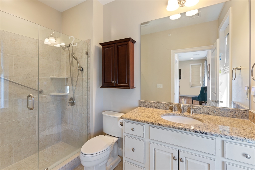 151 HMS Halsted Drive, Unit 151 Hingham, MA 02043 - Photo 36 of 41 a bathroom with a granite countertop sink a toilet and shower