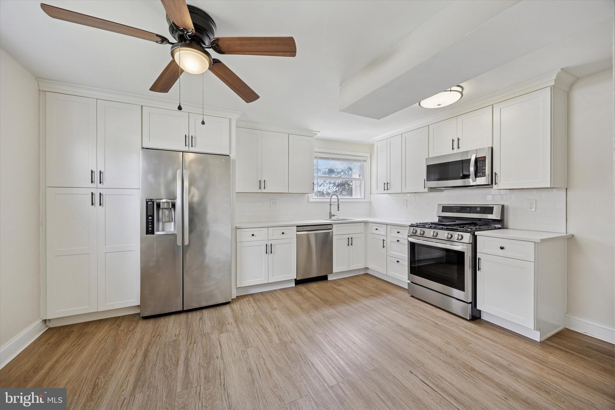 723 Bennington Road Folcroft, PA 19032 - Photo 8 of 25 a kitchen with stainless steel appliances a refrigerator a stove top oven a sink and dishwasher with wooden floor