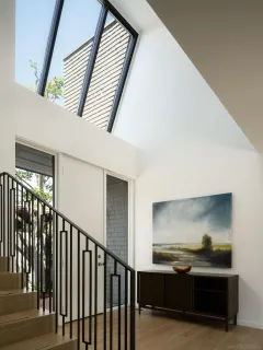 a living room with couches a coffee table a flat screen tv and a large window with kitchen view