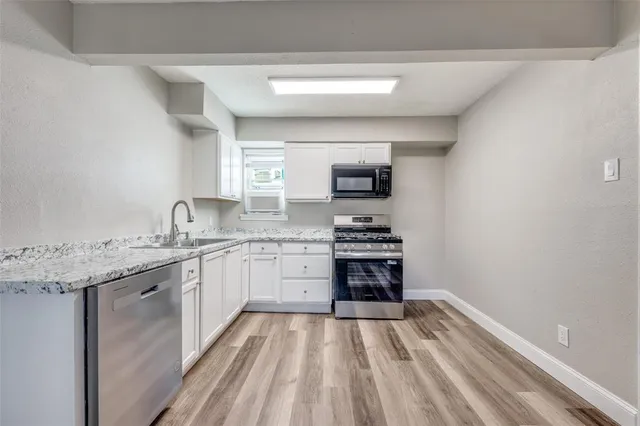 a kitchen with granite countertop a sink stove and cabinets