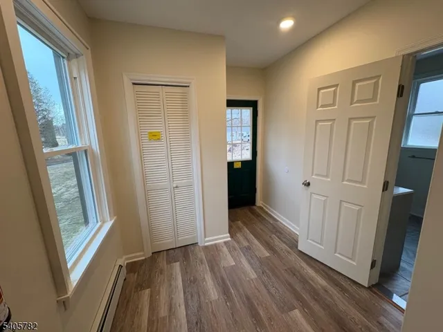a view of a hallway with wooden floor and cabinet