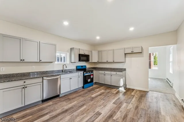 a large kitchen with stainless steel appliances granite countertop a stove and white cabinets