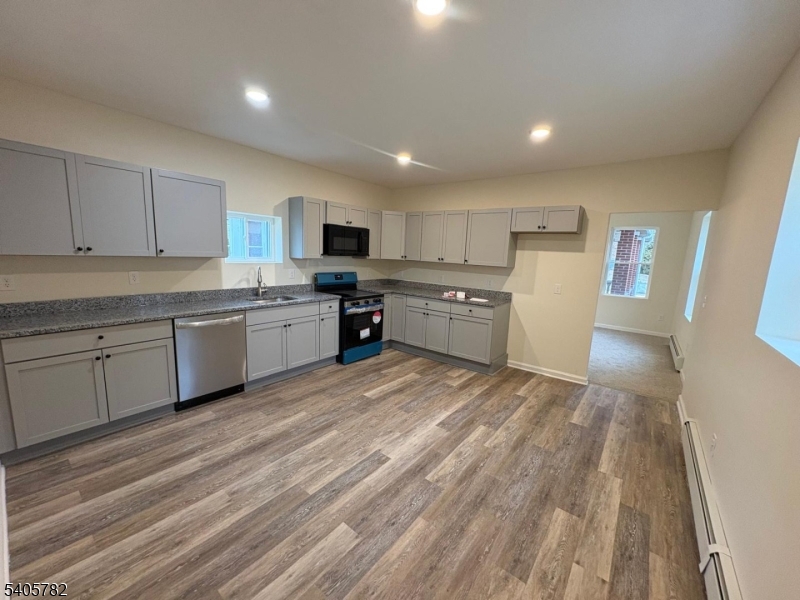 786 South Main Street, Unit 1 Phillipsburg, NJ 08865 - Photo 8 of 18 a large kitchen with a refrigerator a stove top oven a sink dishwasher and white cabinets with wooden floor