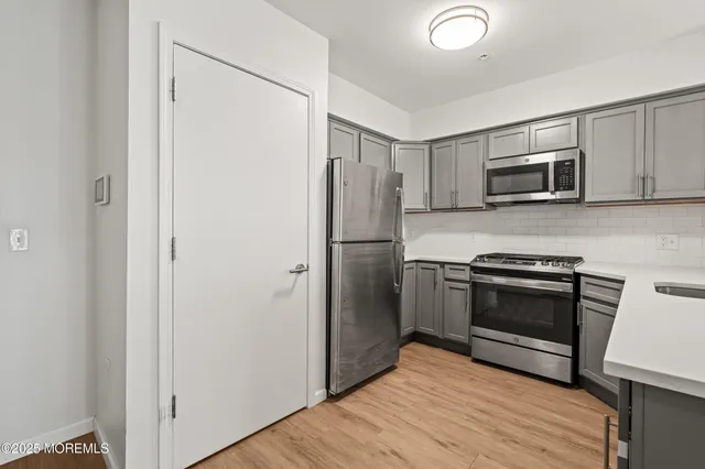 a kitchen with granite countertop a refrigerator and a stove top oven