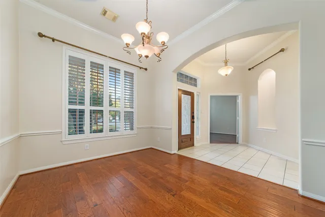 a view of an empty room with wooden floor and a chandelier