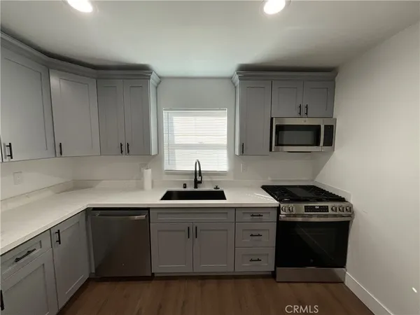 a kitchen with granite countertop a sink a stove and cabinets