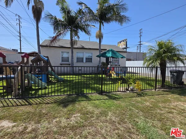 a view of a house with a small yard and wooden fence