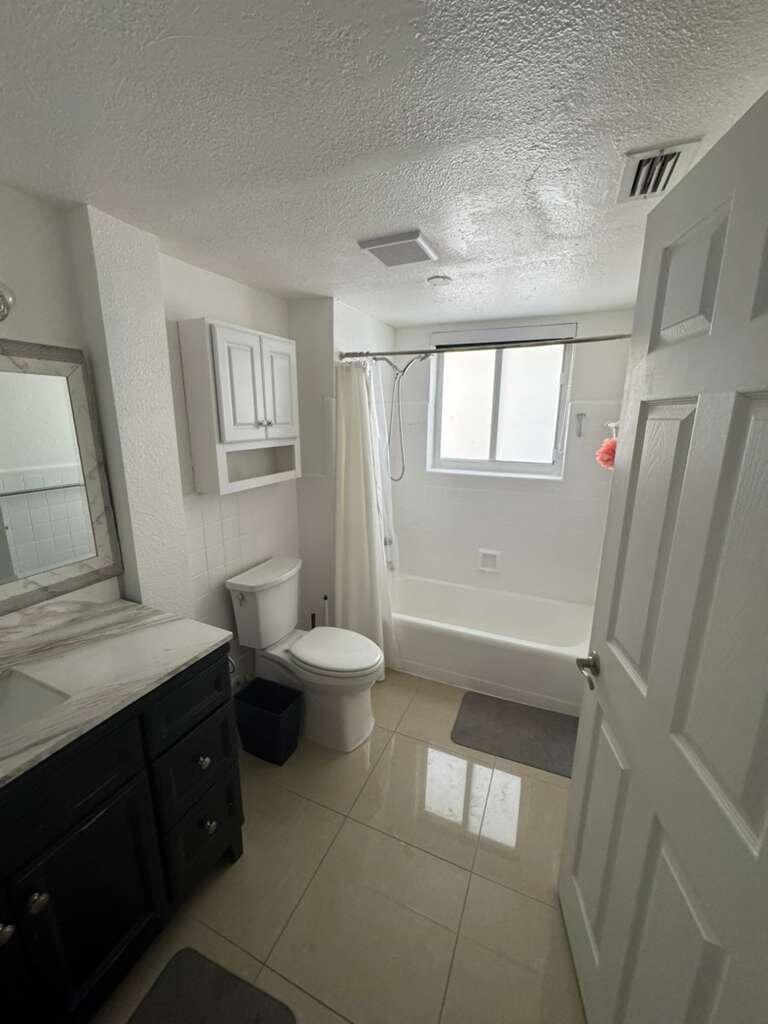 1001 South Riverside Drive, Unit 104 Pompano Beach, FL 33062 - Photo 3 of 6 a bathroom with a sink a toilet and a window