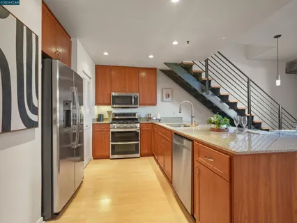 a kitchen with stainless steel appliances granite countertop a refrigerator a stove and a sink with wooden floor