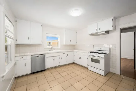 a kitchen with white cabinets appliances and a sink