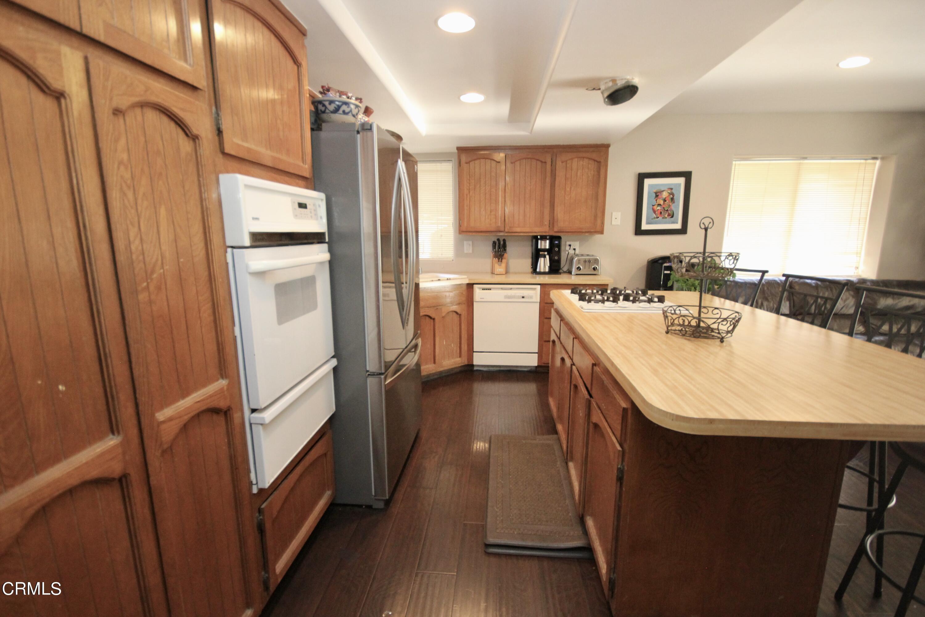1966 Sutter Place Oxnard, CA 93033 - Photo 8 of 19 a kitchen with refrigerator a stove a sink dishwasher and cabinets with wooden floor