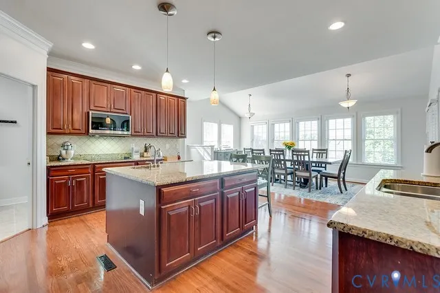 a kitchen with stainless steel appliances granite countertop wooden cabinets a sink dishwasher a stove and a refrigerator