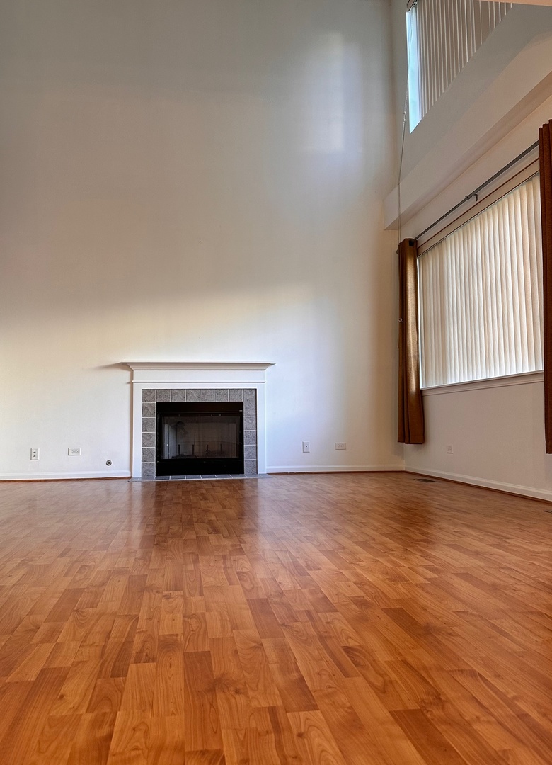 5412 Teaberry Court, Unit 5412 Rolling Meadows, IL 60008 - Photo 5 of 12 an empty room with wooden floor and fireplace