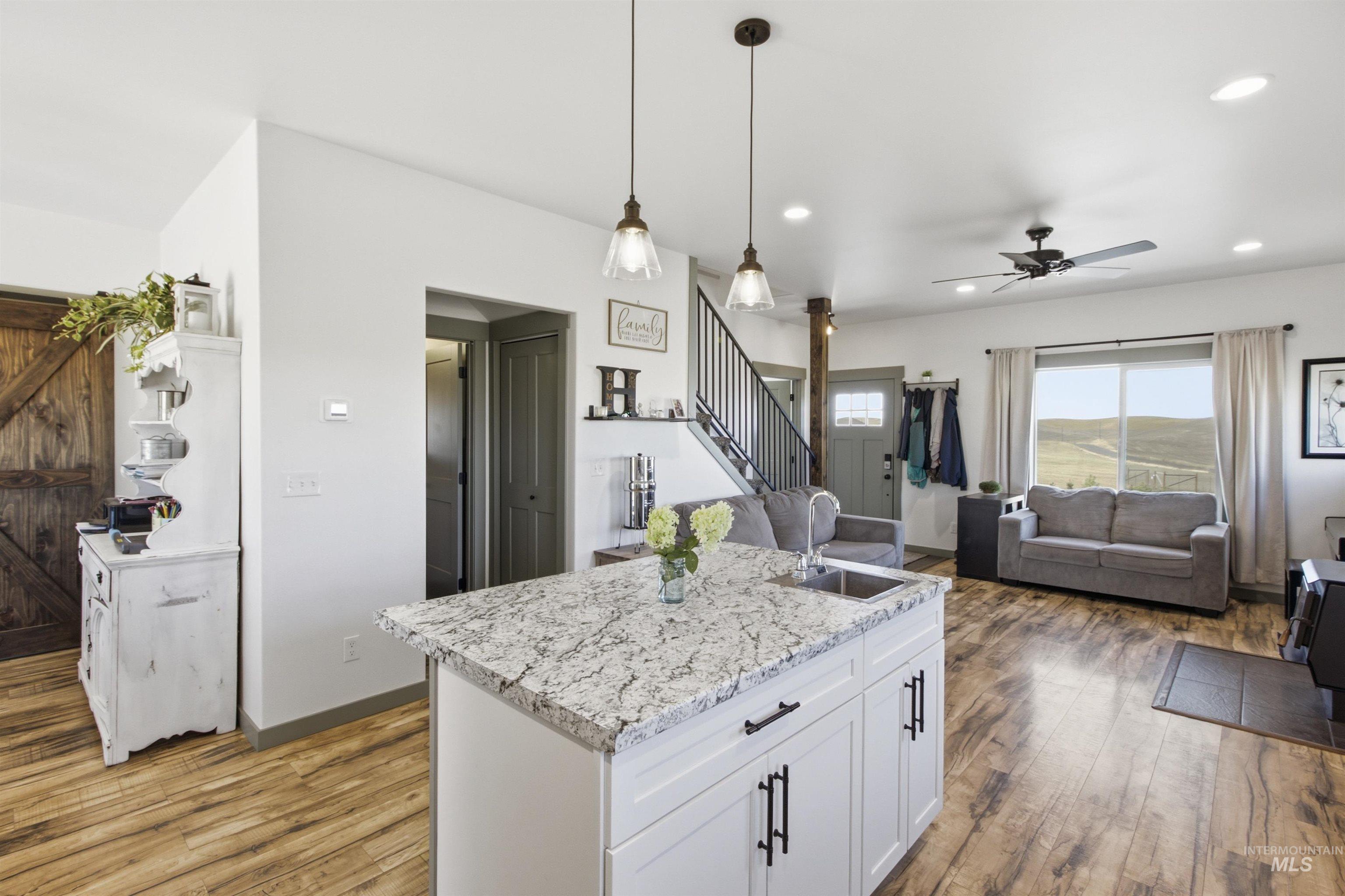 1032 Duffield Flat Road Potlatch, ID 83855 - Photo 10 of 50 Kitchen island with a granite-style countertop and undermount sink, wood-finish flooring, white cabinetry with dark hardware, and recessed lighting