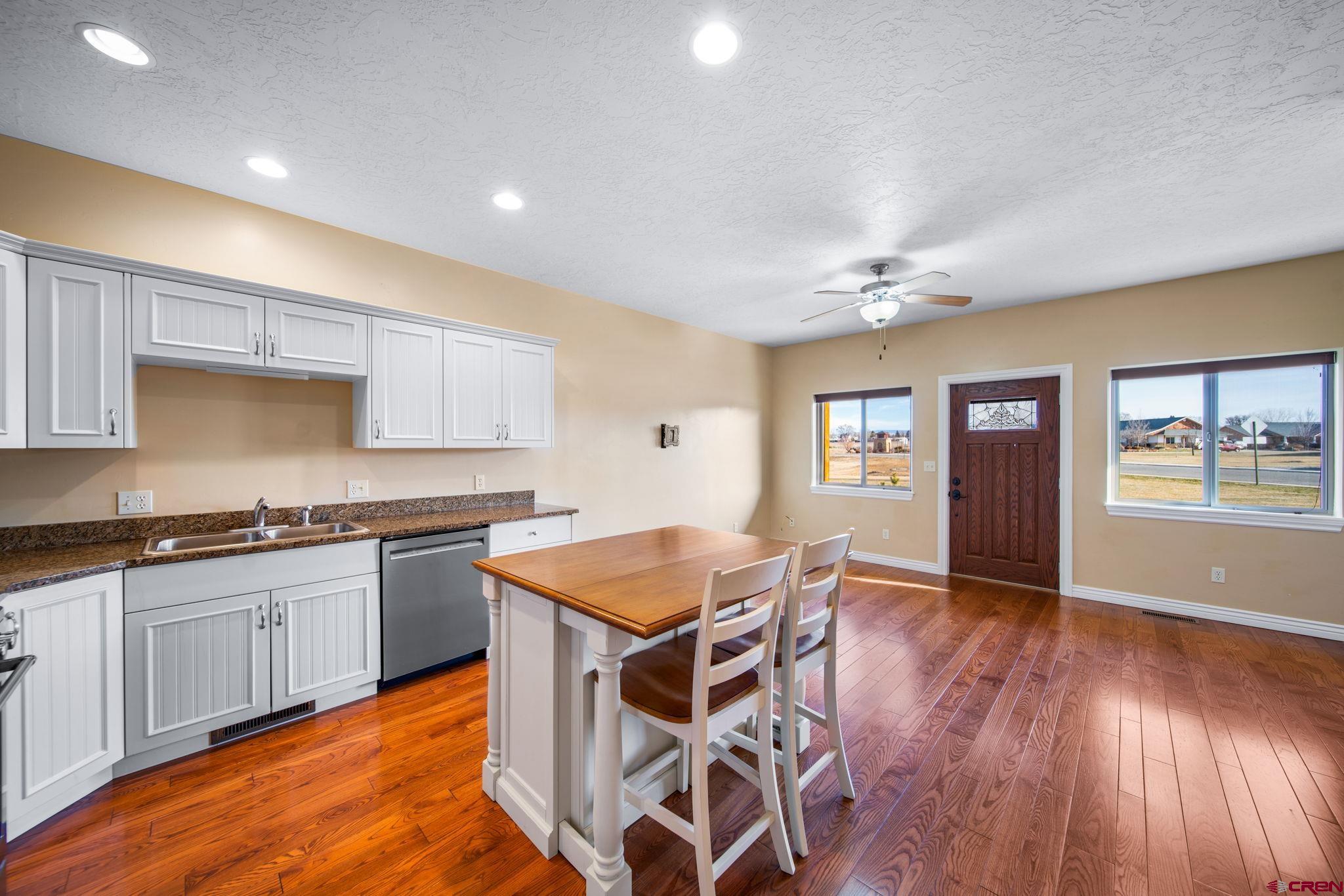 1630 Gateway Drive, Unit 3 Cortez, CO 81321 - Photo 11 of 34 a kitchen with granite countertop a stove top oven a sink dishwasher and white cabinets with wooden floor